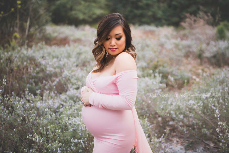 mother posing for a maternity session in a field of flowers