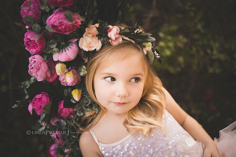 little girl looking left on a bed of flowers