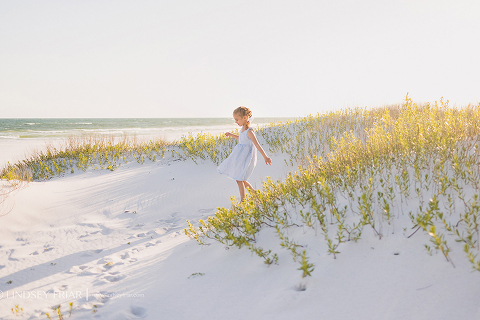 little girl on beach running down a dune