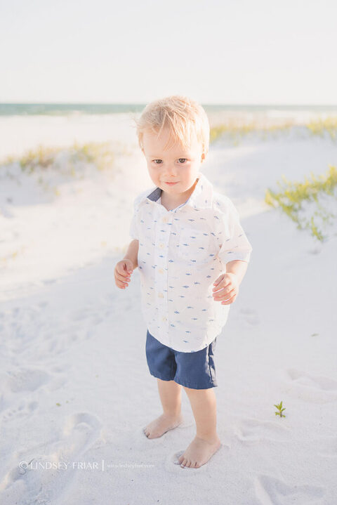 blonde hair 2 year old boy standing on beach